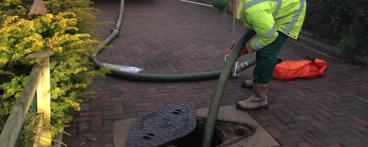 Septic tank cleaning technician servicing a septic tank with a vacuum hose in Savannah, GA
