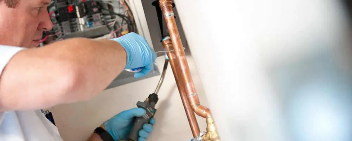 Water heater repair technician testing copper pipe connections and controls in Savannah, GA
